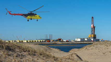 Oil and gas field in the Arctic. Summer. Sandy landscape with small lakes. Drilling rig. Flying helicopter.