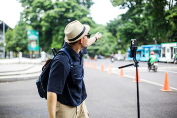 Traveler Man Doing Livestream on Social Media Using Smartphone While Pointing In The City Street 