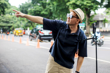 Traveler Man Doing Livestream on Social Media Using Smartphone And Tripod In The City Street