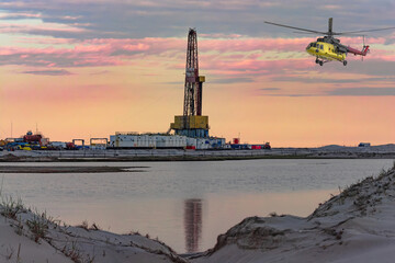 Oil and gas field in the Arctic. Summer. Sandy landscape with small lakes. Drilling rig. Flying...