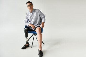 A young handsome man with a prosthetic leg sits in a chair, showcasing his style and confidence.