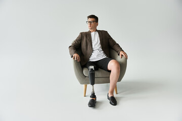 Man sits comfortably in a chair, showcasing a stylish outfit with a prosthetic leg.