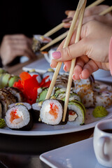 Hand Holding a Piece of Sushi and Lifting It from a Plate