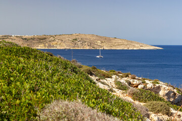 a stunning coastline view at the coast of Comino, Malta. With a small white sailing boat at the Mediterranean sea