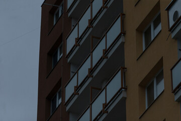 A very tall building featuring numerous windows and balconies stands out impressively against a backdrop of a cloudy sky