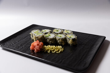 Salmon skin sushi roll served on a black stone, top view