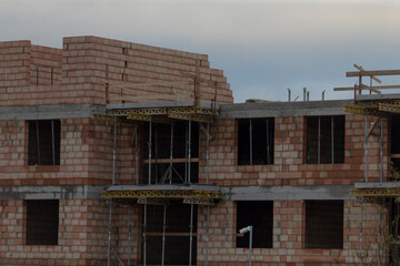 A brick building is currently under construction, with scaffolding set up around it, indicating active work taking place onsite