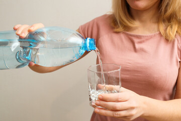 Woman's hands pouring water into glass, close-up. Banner with concept of natural clean aqua at home.