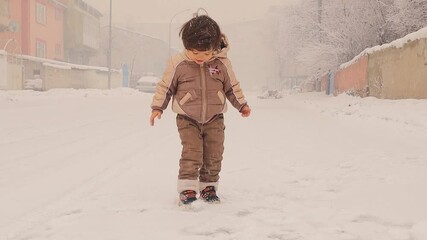 joyful young child jumps with excitement as snow falls gently all around, capturing the pure delight and wonder of experiencing snowfall. A heartwarming winter scene full of happiness and energy.