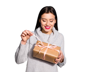 Portrait of cheerful lady pulling ribbon looking at package smiling wearing gray sweater isolated over blue background