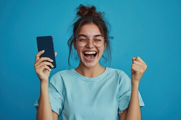 Happy woman celebrating success while holding a smartphone