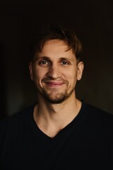 Close-up portrait of handsome young Caucasian man smiling against apartment background