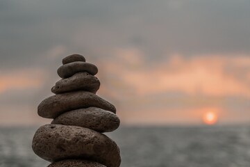 Stones Stack Sunset Beach - A Zen rock cairn balances precariously against a picturesque sunset over the ocean.