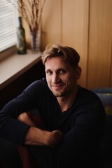 Obraz premium Close-up portrait of handsome young Caucasian man smiling against apartment background