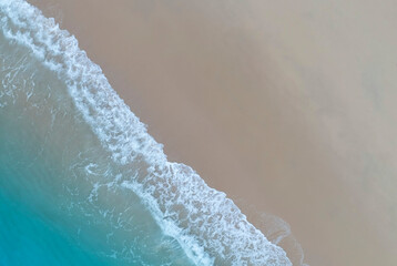 Tropical Beach with the soft wave water of the sea on the sandy beach background as texture with splashes and bubbles