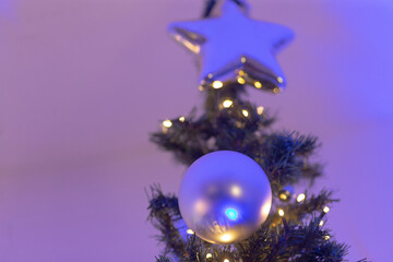 A beautiful Christmas tree adorned with a shining star and a decorative ball positioned elegantly on top of it, creating a festive atmosphere