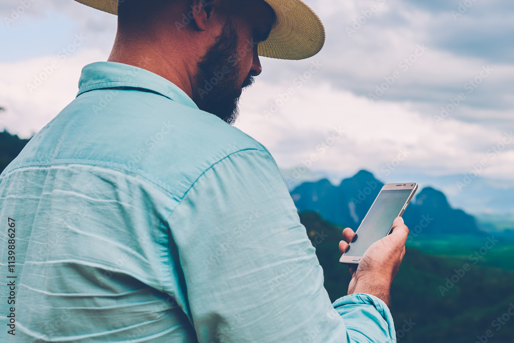 Poster side view of male traveler holding mobile phone in hands and reading message via application during 