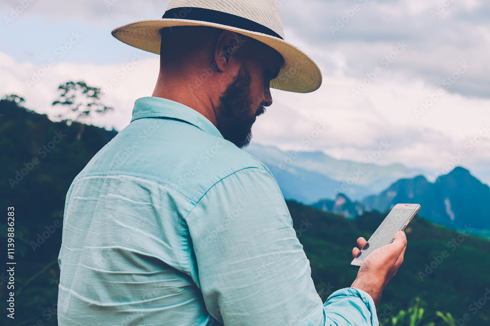 Poster side view of male traveler holding mobile phone in hands and reading message via application during 