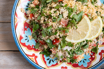Tabbouleh salad with couscous on wooden table. Top view