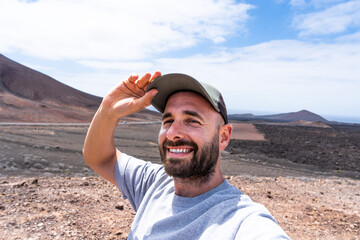 Selfie male traveler enjoys a sunny day while exploring a volcanic landscape