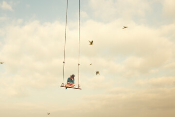 woman on a swing in the sky reading a book, abstract concept