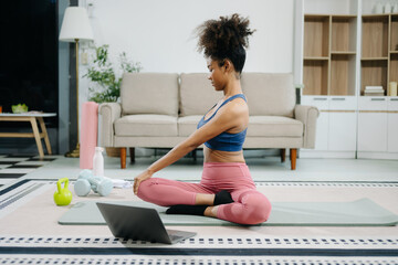 A young woman practices yoga and stretching with a mat and gym props, showcasing wellness,...