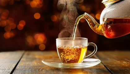 Fototapete Rund Tea time. pouring hot golden drink from glass teapot, modern © Ant