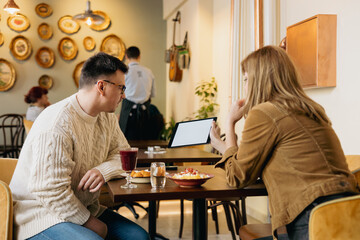 Colleagues having business lunch and using tablet with blank screen in restaurant