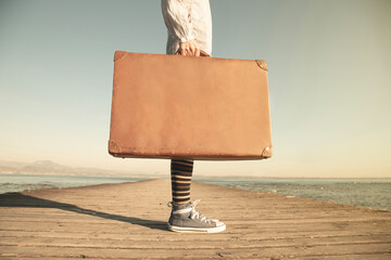 hipster woman traveler with suitcase on a pier; concept of freedom