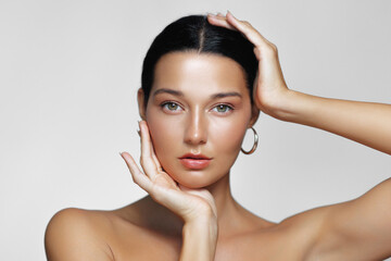Closeup of a Latina woman with glowing skin, sleek hair, and a graceful pose, framed by her hands. Perfect for beauty, skincare, or cosmetics-related marketing materials. 