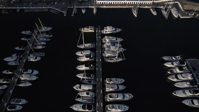 "Drone footage at sunset over La Duquesa Port in Sabinillas, M&aacute;laga. A bird's-eye view advances over the marina, showcasing docked boats, the harbor, and the serene coastal charm."