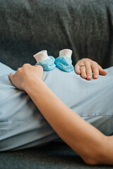 young pregnant girl lying in bed and lie on my belly baby socks