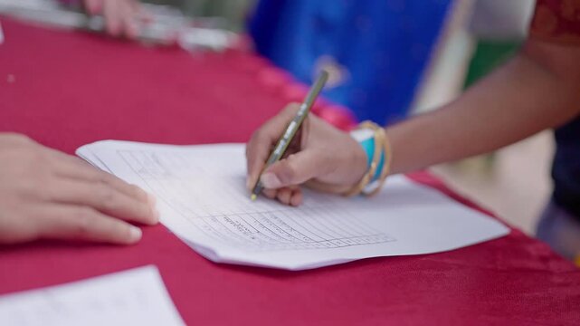 A close-up video of a college student&rsquo;s hand writing personal information on a form with a pen