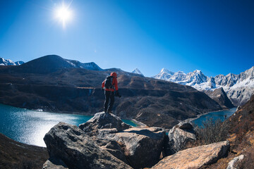 Backpacking woman photographer on high altitude mountain top cliff edge