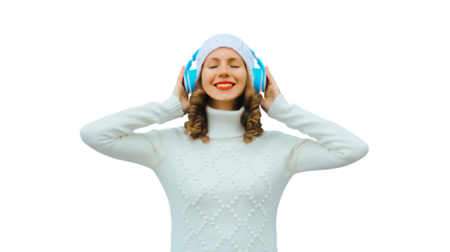 Portrait happy inspired young woman enjoying listening to music in headphones in white hat, sweater