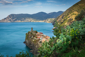 Naklejka premium Vernazza village at sunrise with colorful houses perched on cliffs overlooking the Ligurian Sea. Warm golden light highlights the charm of this scenic Cinque Terre coastal landscape.