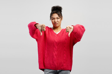 Displeased young woman showing thumbs down gesture expressing dislike