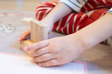 Obraz premium The child plays with wooden bars, making shapes out of them. Eco-friendly toys for children made of natural wood.