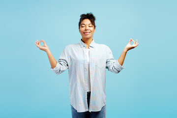 Young woman meditating with closed eyes and gyan mudra hand gesture on blue background