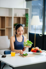 wellness as a cheerful woman enjoys a salad and fruits while engaging with technology at home