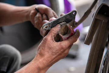 Mechanic sitting focused using wrench to repair motorcycle brake, drum brake pads at repair shop