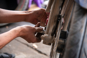 Mechanic sitting focused using wrench to repair motorcycle brake, drum brake pads at repair shop