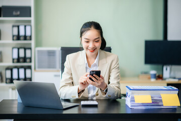 Obraz premium Asian woman talking on the phone with a customer Young positive female accountant using smartphone talking