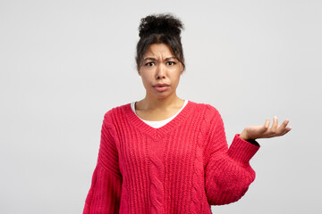 Confused young woman shrugging shoulders on white background