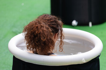 Girl immersing herself in little Circular Pool Filled with Water and Ice: Ice Baths and Wellness