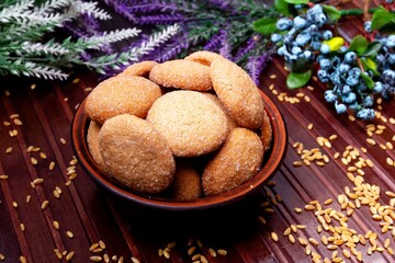 homemade cookies in a clay plate, wheat, herbs and berries on a brown background