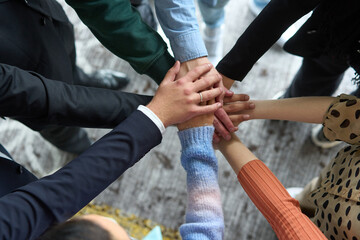 A top view of business people joining hands in a circle, symbolizing unity, collaboration, and shared success in the workplace