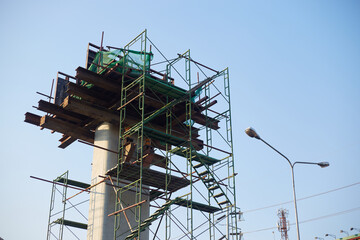 Construction of a high-rise building with scaffolding and construction equipment on blue sky background