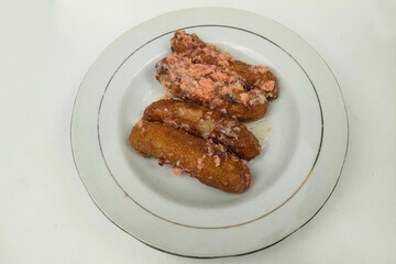 Banana cake is served on a white plate on a white table