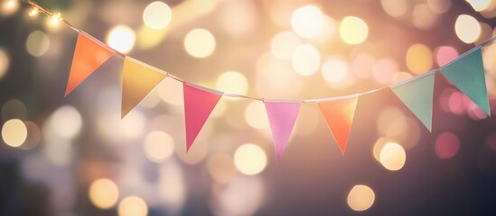 Colorful party bunting flags with blurred bokeh lights creating a festive background suitable for holiday celebration and text overlay space
